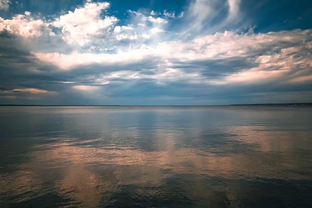 Dreamy photo of a lake with a blue sky and clouds. Evokes calm stillness and serenity.