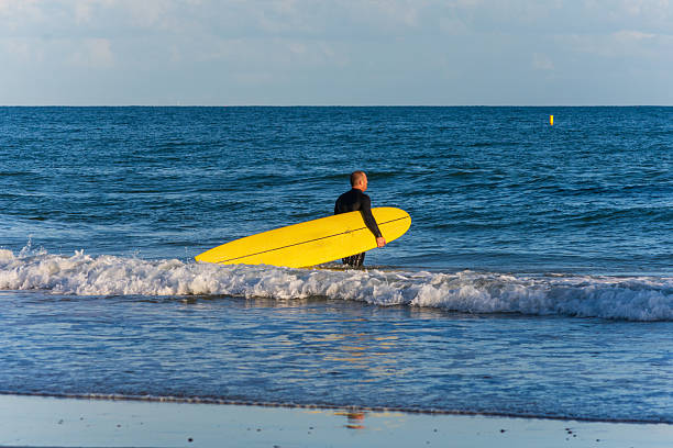 East Cliff Beach, Bournemouth, UK - September 22nd 2025: Surfer walking with their surfboard into the sea.