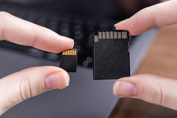 istock Human hands holding micro SD and standard SD cards, comparing their distinct sizes for diverse digital data storage across electronic devices 2240576387