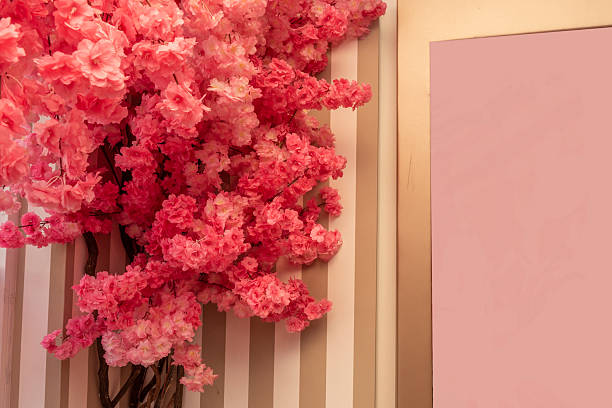 Lot of pink artificial flowers on a striped painted wall