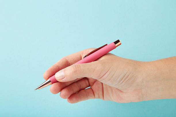istock Young woman holding pink pen on blue background. 2240584667