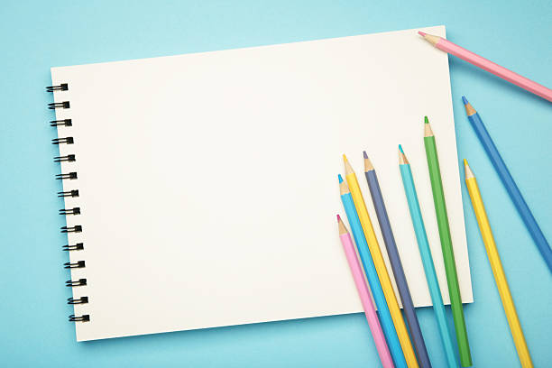 istock Sketchbook and colored pencils on blue background 2240584680