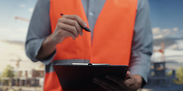 istock Construction Worker Holding Clipboard in Vibrant Orange Vest 2240584830