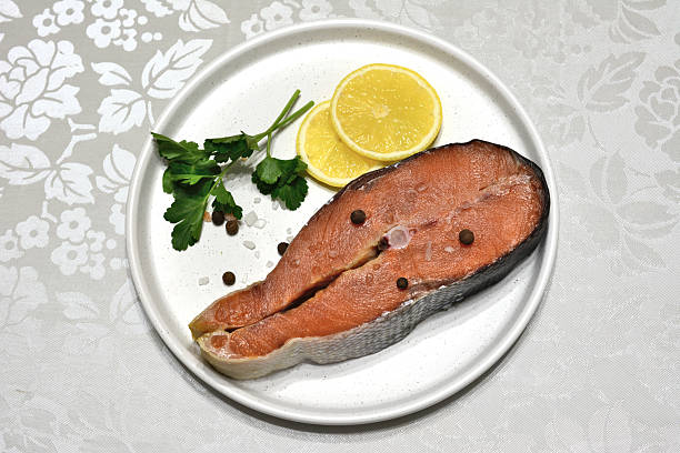 istock Raw Salmon Steak with Lemon and Herbs on a White Plate 2240590319