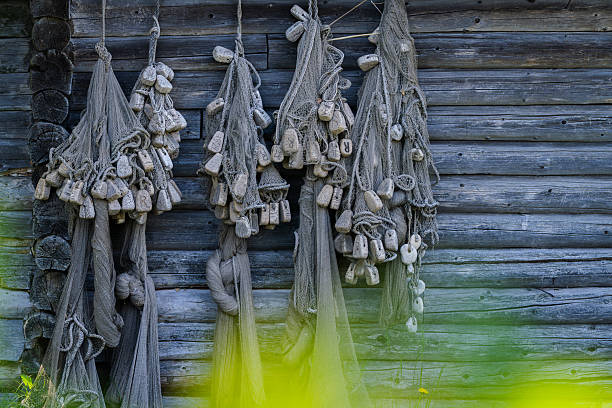 Old vintage fishing nets background. Authentic used fishing nets hanging on a wooden wall. Decorative nautical decor.
