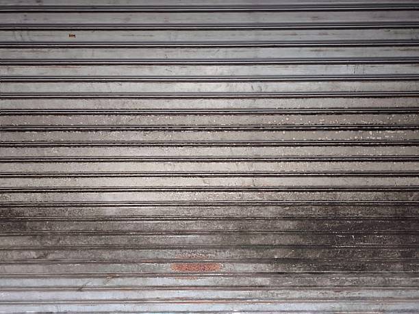 istock Old metal rolling shutter door. Industrial steel texture shows aging. For backgrounds, architectural design elements, and industrial or vintage themed projects 2240597957