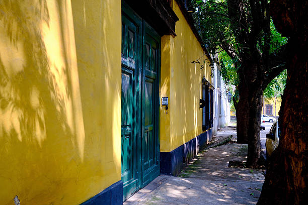 istock Dappled Sunlight on Yellow Wall With Green Door (Mexico City, Mexico) 2240605467