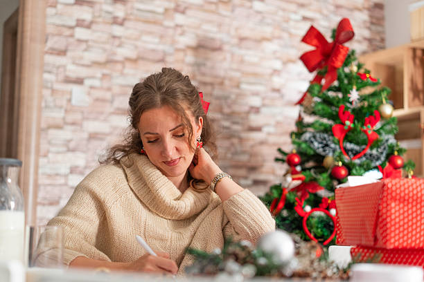 istock Woman writing christmas letter near decorated tree 2240607224