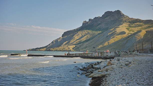 istock Tourists relaxing on Koktebel beach under Kara Dag mountain in Crimea 2240610911