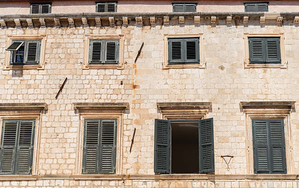 istock Green louvered window shutters on stone facade 2240611725