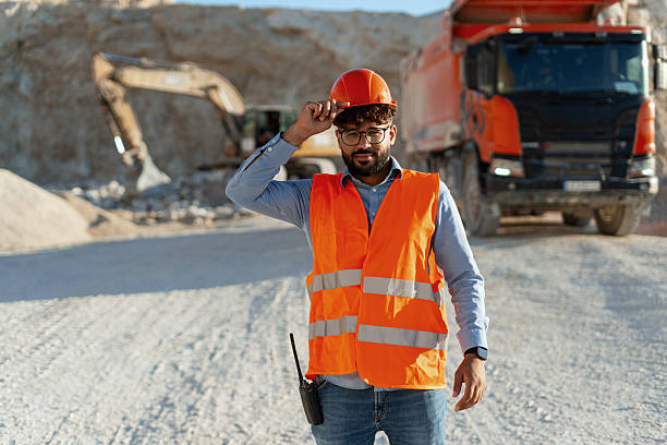 istock Confident Middle Eastern engineer wearing orange helmet and vest, standing on mining site 2240612320