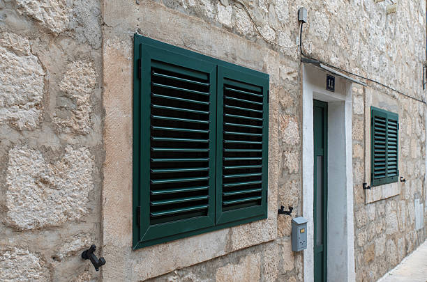 istock Green louvered shutters on stone facade 2240613703