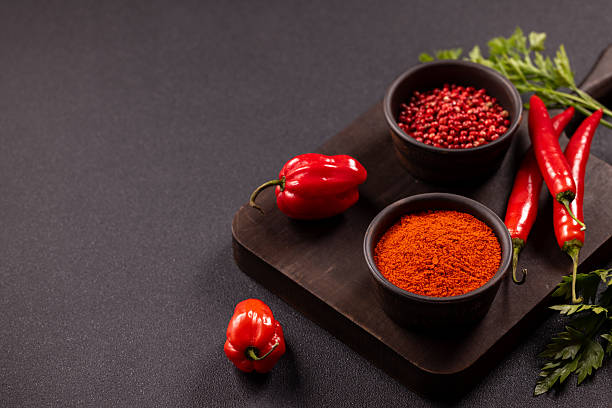 istock Red chili peppers and spices on dark board 2240613978