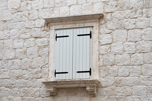 White wooden window shutters stone frame