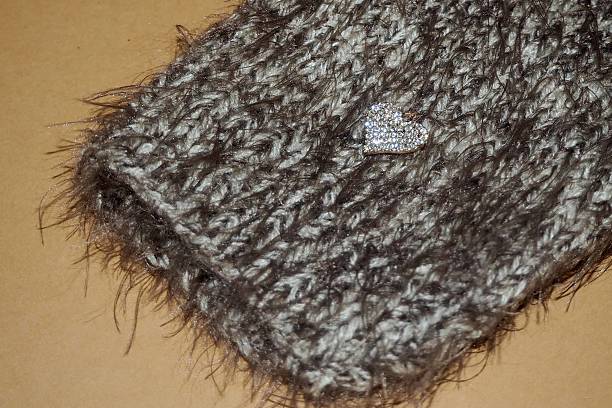 istock Handmade gray knitted dog sweater bottom part with a shiny heart accessory, soft fluffy texture, and cozy winter design on a light background. 2240618286