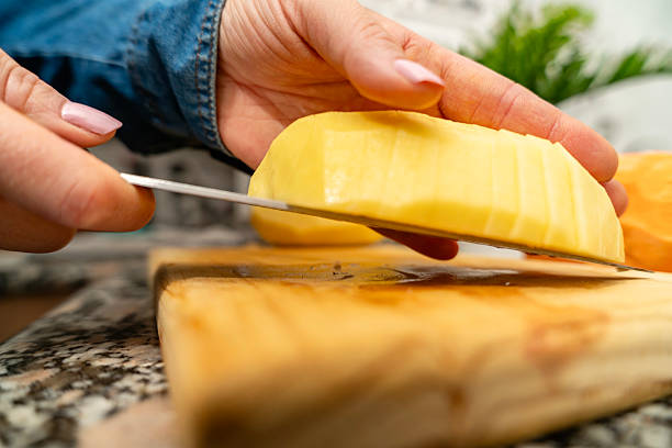 istock Human hands slicing potato on cutting board for cooking 2240618583