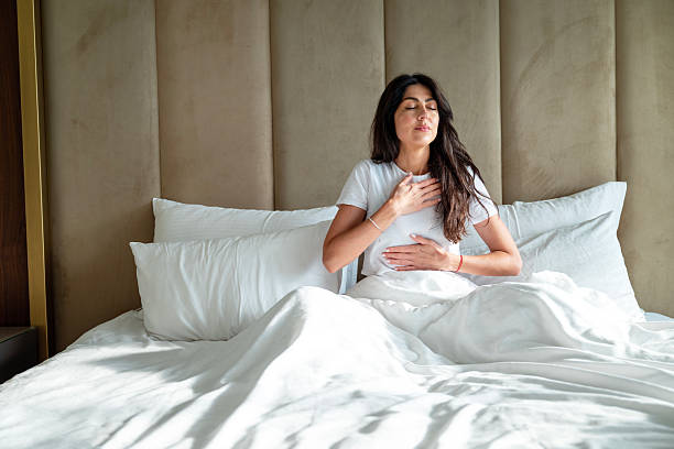 istock Young Woman Practicing Breathing Exercise in bed for Relaxation 2240618946