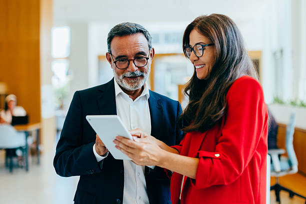 istock Mature businessman and female executive using a tablet in a bright office 2240619270