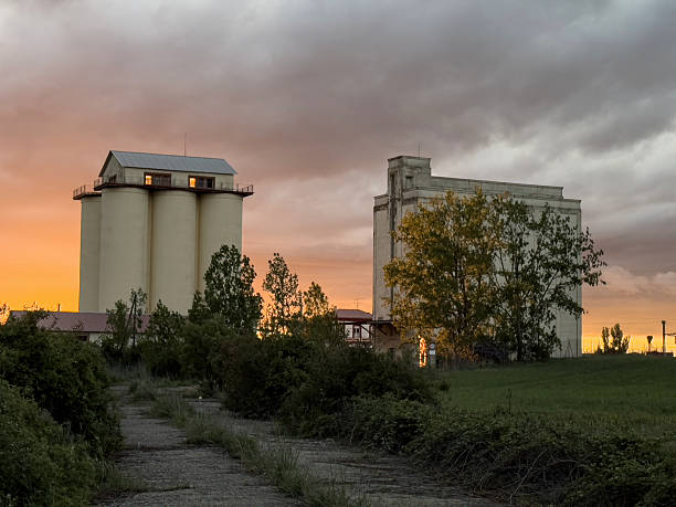 istock Old grain silos with rooftop structure at sunset in rural landscape 2240619508