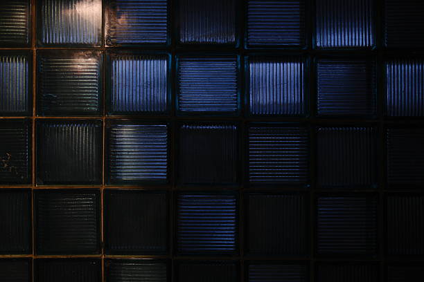 Light reflects off of dark glass blocks. The blocks are square shaped and uniform.