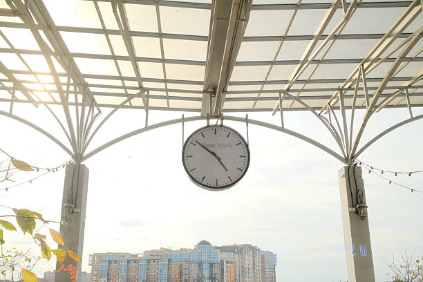 NYC clock under metal, buildings behind.