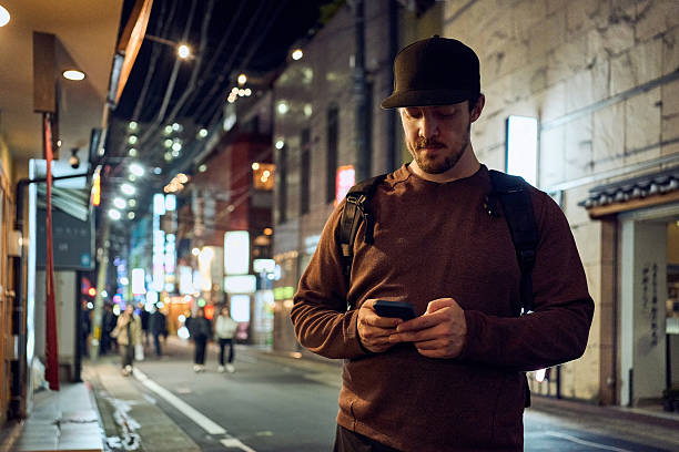 istock Man in cap using smartphone on city street at night 2240621292