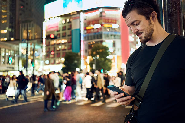 istock Man using phone on city street at night during vacation 2240622481