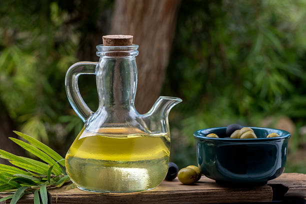 Black and green olives in round bowls, on a rustic wooden background with leaves and olive oil