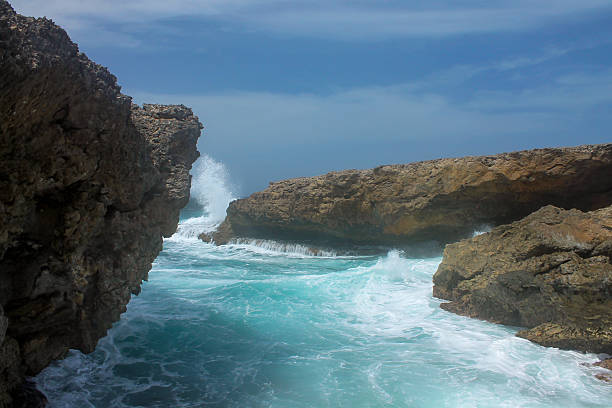 A sunny day, the water calms down for a moment before the next wave rushes between the rocks