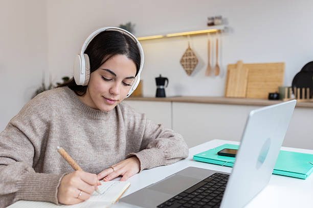 istock Focused student learning online, taking notes and wearing headphones 2240626747