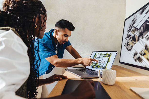 istock Two architects discussing a residential project while reviewing architectural plans on a laptop 2240631156