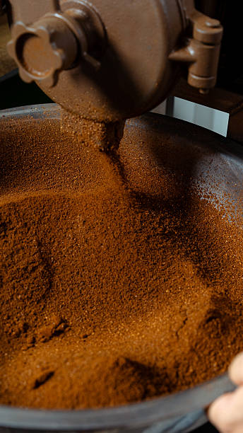 Grinding machine processing roasted coffee beans into fine powder, filling a container
