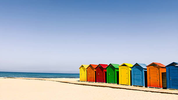 istock Colorful Beach Huts On Sandy Shoreline 2240634110