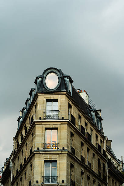 Classic Parisian Apartment Building Under Cloudy Sky. Urban exterior for architecture or travel context. For illustrating city living or European housing.