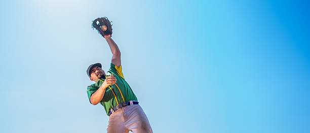 Boy concentrating on catching a baseball during a jump while playing outdoors