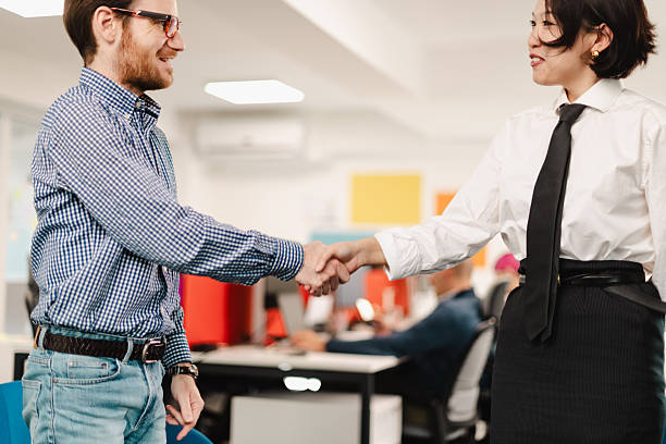 istock Business meeting showing handshake between two professionals in a modern office setting during daytime with colleagues engaged in work 2240650531