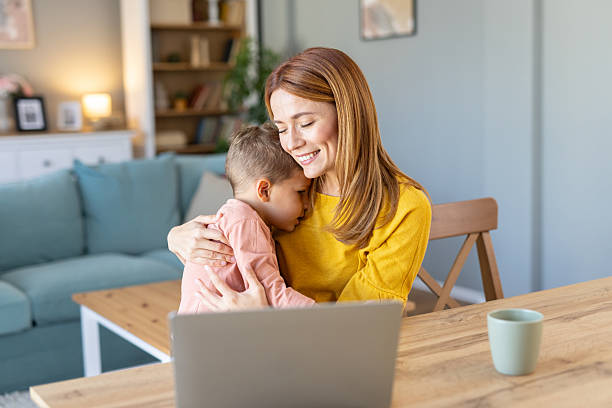 istock Mother embracing child while watching on the laptop screen 2240652124