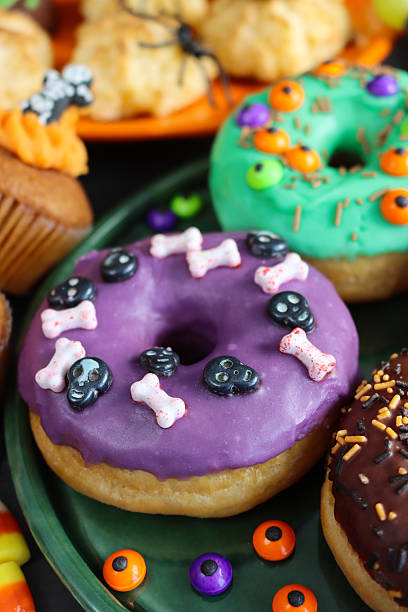 istock Image of halloween party iced ring doughnuts with candy decorations / spooky fun cakes, festive dessert treats 2240653918