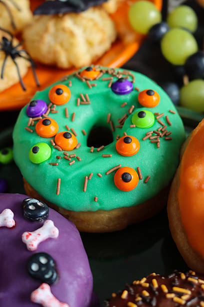 istock Image of halloween party iced ring doughnuts, candy decorations / spooky fun cakes, festive dessert treats, creative holiday food 2240653950