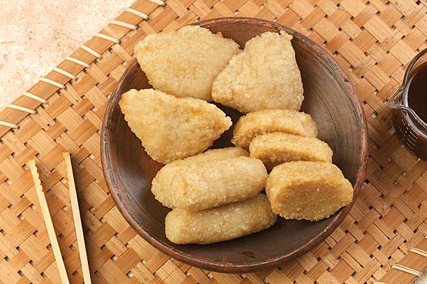 Authentic Indonesian pempek dish on bamboo mat with cup of cuko vinegar sauce beside it. Perfect for Asian food and culture themes.