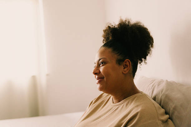 istock Woman sitting by the window at home 2240664447