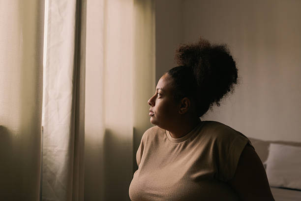 istock Plus size woman sitting on bed near curtains 2240664455
