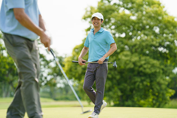 istock Senior and young golfers walking on fairway, discussing golf game. 2240671546