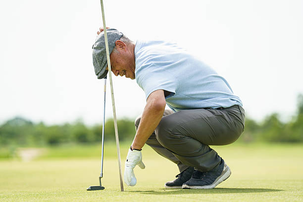 istock Senior golfer collecting ball from hole after successful putt. 2240671562
