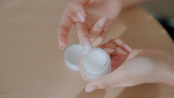 istock Young woman scooping up skincare product while doing her beauty routine. 2240678333
