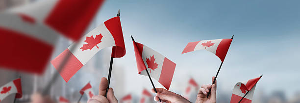 istock Canada flags in their hands on a blurred urban background 2240678335