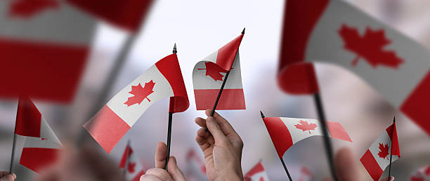 istock Canada flags in their hands on a blurred urban background 2240678342