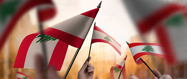 istock Lebanon flags in their hands on a blurred urban background 2240680335
