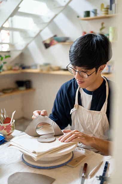 istock Young man potter artist taking out a circle cut clay on working table in a pottery class or studio. 2240684085