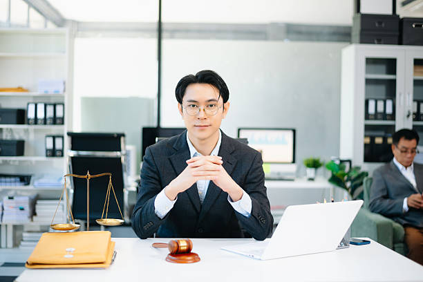 istock Confident Asian lawyer using tablet with gavel and justice scales on desk, looking at camera. Perfect for law, justice, business, and modern legal technology themes. 2240684191